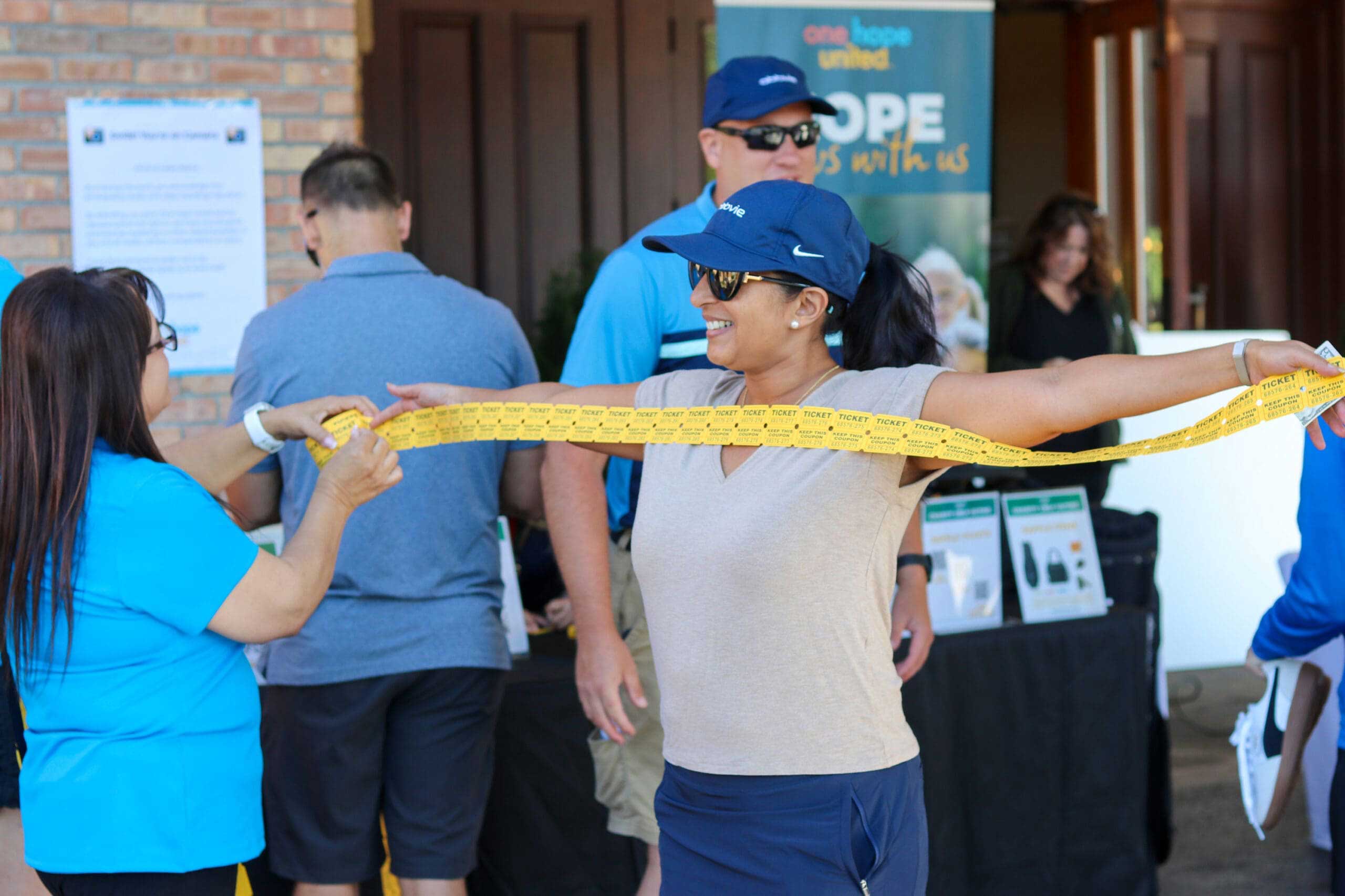 A woman measuring raffle tickets with her arm's wingspan at One Hope United's Charity Golf Outing.