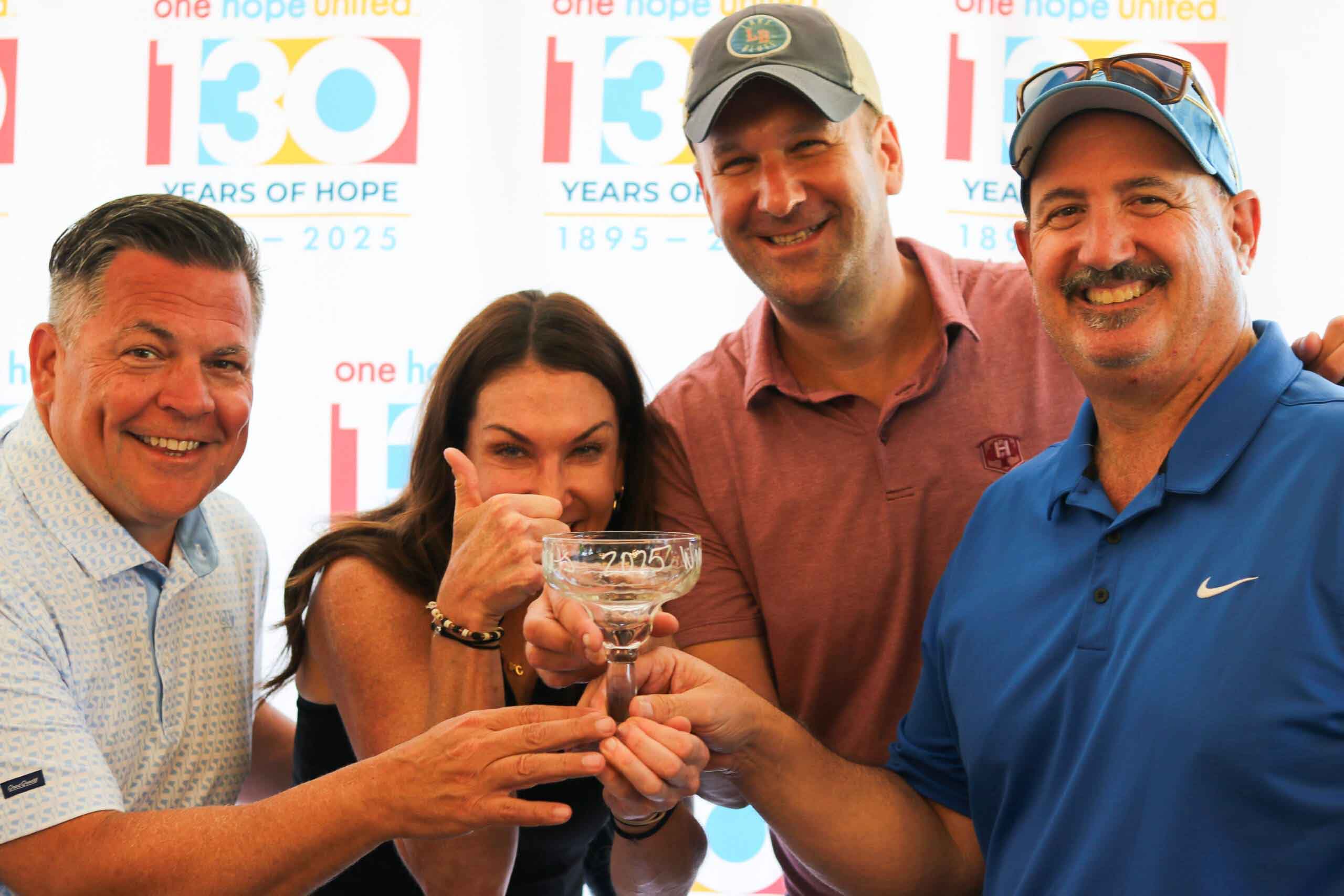 A group smiles with their trophy at One Hope United's Charity Golf Outing.