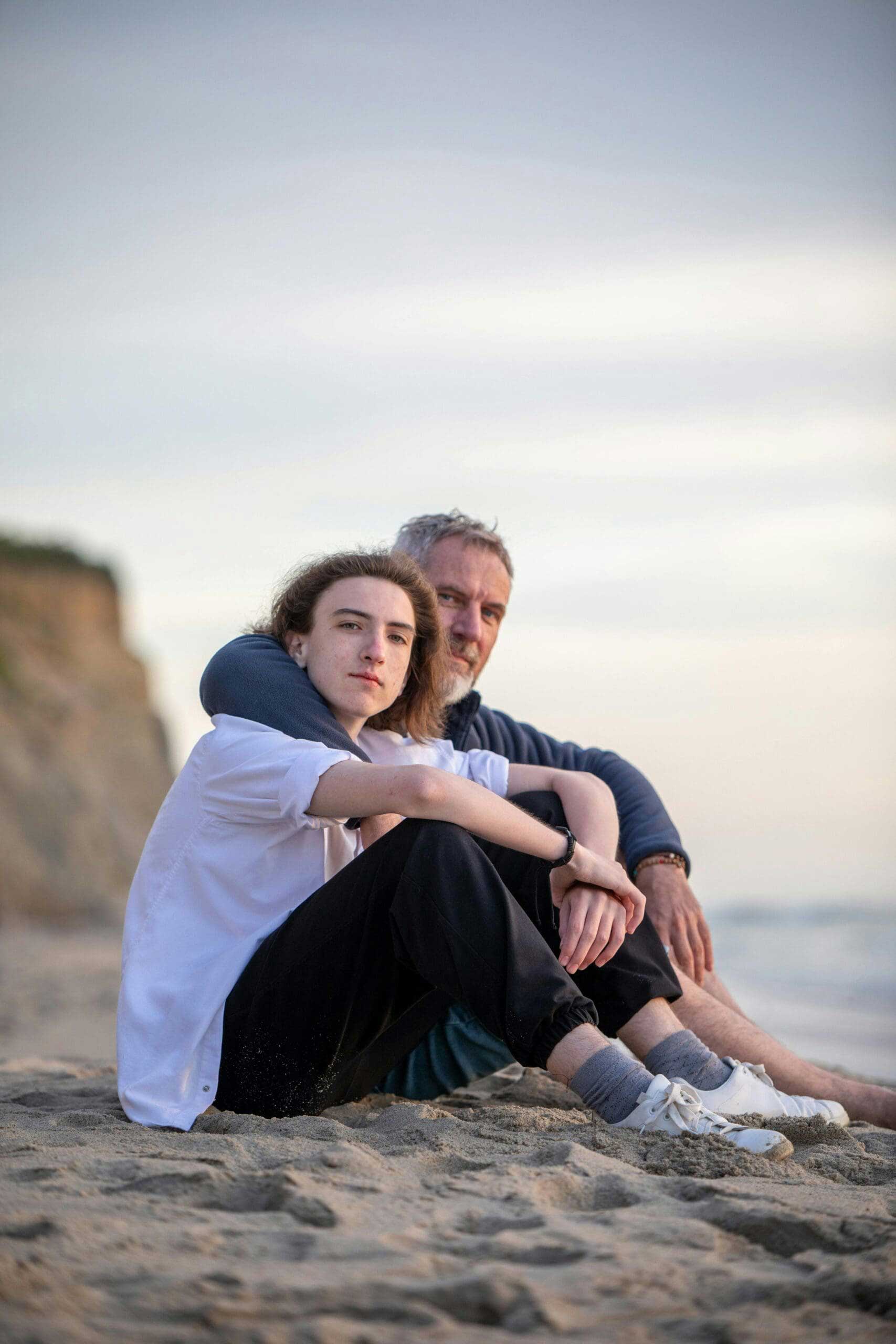 A touching scene of a father and son bonding on a sandy beach during the day.